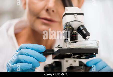 Defocused female scientist looking through microscope Stock Photo