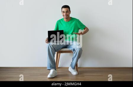 Website advertisement. Excited arab guy showing blank computer screen, recommending website or online service Stock Photo