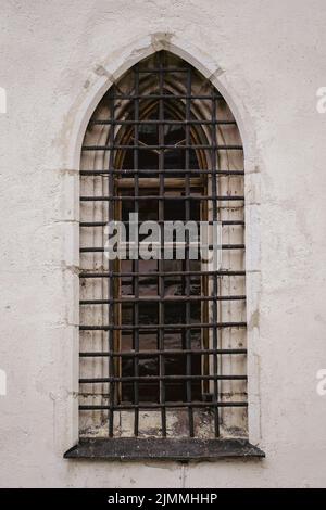 Old white stone wall with one arched grating window on the street in Austria Stock Photo