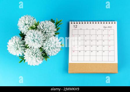 December 2022 calendar with numbers and blue flowers decoration on soft light blue background. Flat lay. 2022 December calendar on blue backgrounds. Stock Photo