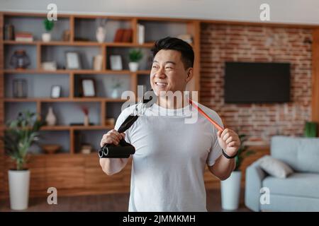 Active sporty lifestyle. Happy asian mature man holding resistance bands hang around his neck Stock Photo