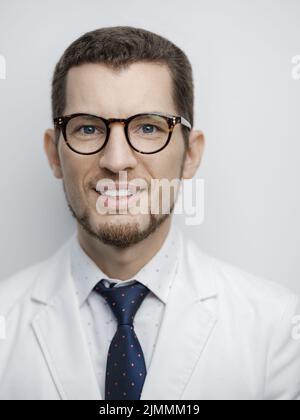 Portrait of happy young bearded male doctor smiling with eyeglasses isolated on white background Stock Photo