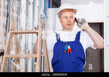 Construction worker having serious phone conversation at indoors building site Stock Photo
