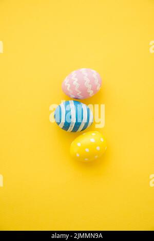 Three colourful easter eggs yellow table Stock Photo