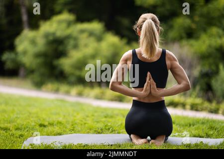 Rear view of sporty woman practicing yoga at park Stock Photo