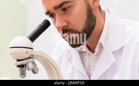 Scientist is using microscope in a laboratory during research Stock Photo