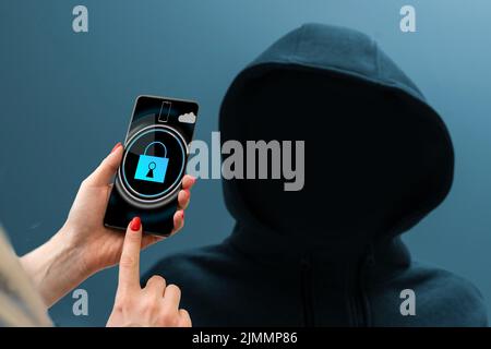 man in a hood Hacker, smartphone with a lock Stock Photo