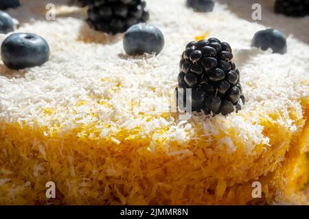 Close-up of a delicious homemade carrot cake decorated with grated coconut, blackberries and blueberries, suitable for vegetarians and vegans. Stock Photo