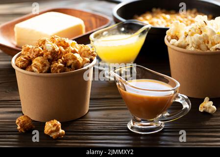 Paper buckets with butter and caramel popcorn on kitchen table Stock Photo