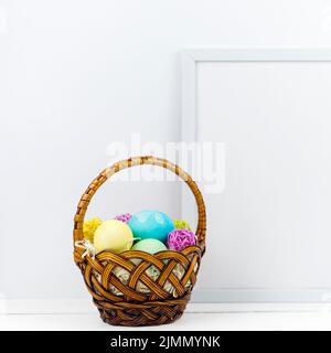 Basket with easter eggs near frame table Stock Photo