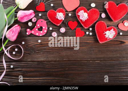 Sewed handmade fabric hearts tulips and ribbon for valentine day on dark wooden background with copy space Stock Photo