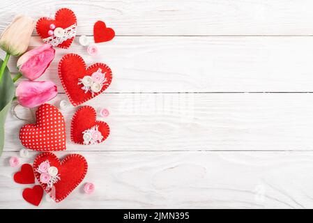 Handmade sewed Valentine fabric hearts and tulips  flat lay background on white wooden table with copy space Stock Photo