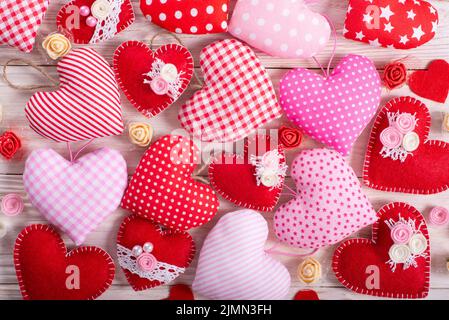 Sewed handmade fabric hearts for valentine day on white wooden background Stock Photo