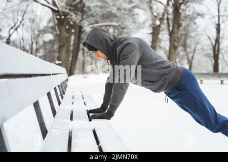 Athletic man doing push ups during his calisthenics winter workout Stock Photo