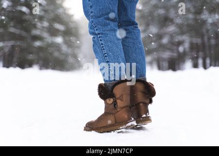 Woman wearing sheepskin boots walking by snowy road Stock Photo