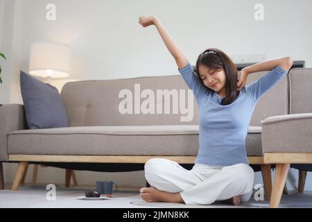 Work from home concept, Business women sit on floor and stretching to relax after working at home. Stock Photo