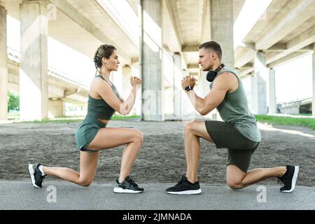 Athletic couple doing lunges during street workout Stock Photo
