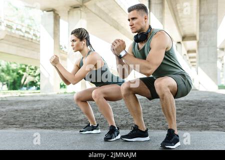 Athletic couple doing squats during street workout Stock Photo