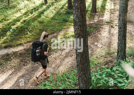 Female hiker with big backpack in green forest Stock Photo