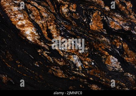 Black Magma granite texture in dark color with brown surface. Stock Photo