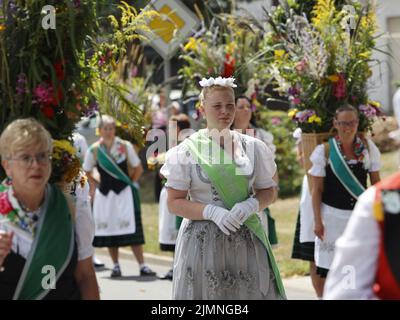 07 August 2022, Saxony-Anhalt, Hüttenrode: Kim Fischer, the new Grass Queen, walks through the village in the 'Grasedanz' pageant. The Grasekönigin has been elected in Hüttenrode every year since 1885. The custom festival, which focuses on women, is celebrated annually on the first weekend in August. Photo: Matthias Bein/dpa Stock Photo