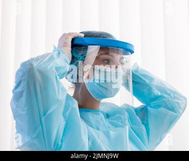 Side view woman doctor putting protective wear Stock Photo