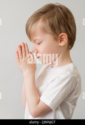 Side view little boy praying Stock Photo