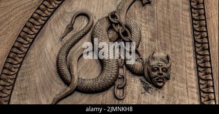 Devil snake symbol. Fantasy magic creature on an old door, 12th Century Abbey in Italy. Stock Photo