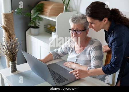 Senior women learning to use computer at home helped by a young women Stock Photo