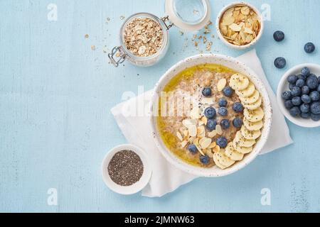 Oatmeal with blueberries, banana on blue light background Stock Photo