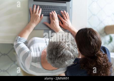 Young and senior women working on computer. Image taken from above Stock Photo