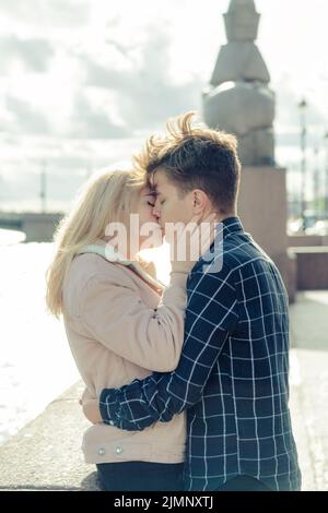 The boy looks tenderly at girl and wants to kiss. A young couple stands embracing. The concept of teenage love and first kiss, s Stock Photo