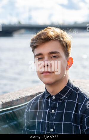 Portrait of young guy, brunette with dark hair, Caucasian. Close - up of a guy, boy, man looking at camera. Outdoor in city by w Stock Photo