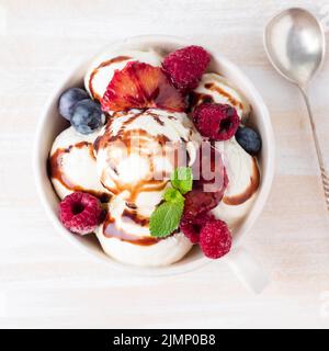 Balls of vanilla ice cream in mug with raspberry and blueberries Stock Photo