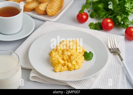 Scrambled eggs, omelet, side view. Breakfast with pan-fried eggs, glass of milk Stock Photo