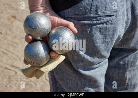 07 August 2022, Schleswig-Holstein, Lübeck: A participant holds three boules balls in his hand. The Holstentorturnier is considered the largest German boules tournament. Photo: Georg Wendt/dpa Stock Photo