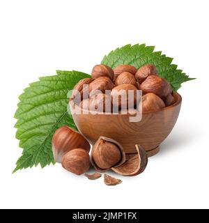 Bowl of hazelnuts with green leaves isolated on white. Deep focus Stock Photo