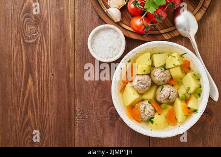 Meatballs soup in white plate on old wooden rustic brown table, top view Stock Photo