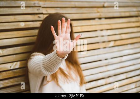 Woman with long hair reaches forward, shielding her face from camera. Concept of privacy, personal space, prohibition of photogr Stock Photo