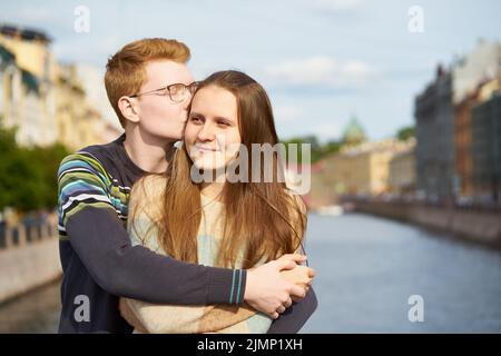 Red-haired man kisses a woman on her hear, a boy in a sweater comforts a girl with long dark thick hair Stock Photo
