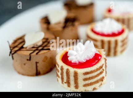 Small cakes with different stuffing on white plate Stock Photo