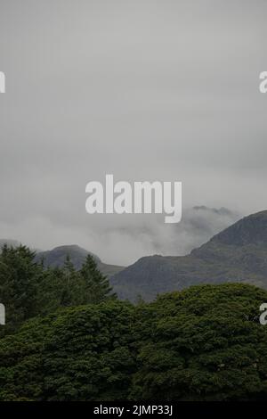 Dramatic clouds and trees over mountains in the Lake District Stock Photo