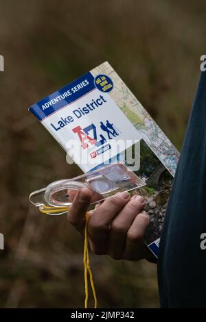 A-Z map and compass in man's hand exploring in the Lake District Stock Photo