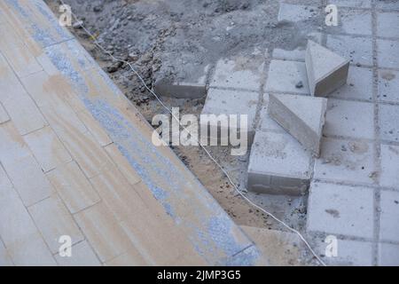 Pavement repair and laying of paving slabs on the walkway, stacked tile cubes on the background. Laying paving slabs in the pedestrian zone of the Stock Photo