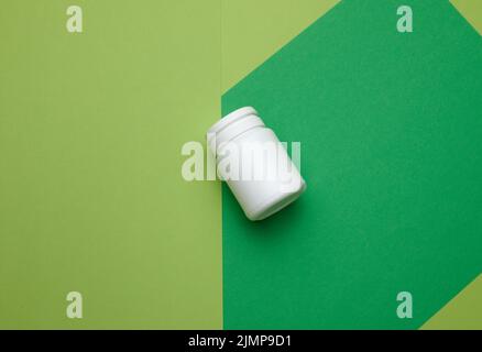 White plastic jar for pills, cream and medicines on a green background. Container for substances, top view Stock Photo