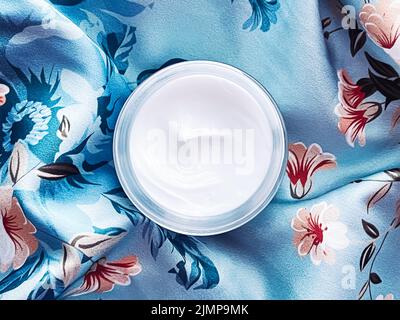 Skincare cosmetics, face cream moisturiser jar on blue floral background, beauty product flatlay Stock Photo