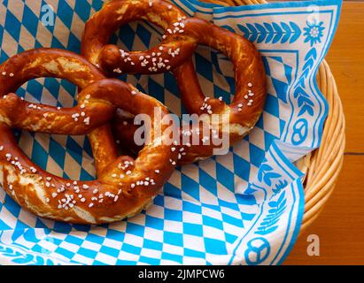 Delicious Bavarian Brezeln or pretzels with a brown salty crust on a traditional Bavarian cocktail napkin in a basket Stock Photo