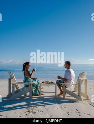 Couple men and women on the beach having coffee and fruit for breakfast , Praslin Seychelles tropical island with withe beaches Stock Photo