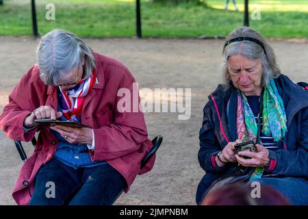 Two Senior Women Using Mobile/Smart Phones Wait For The Queen's Birthday Parade To Begin, Platinum Jubilee Celebrations, The Mall, London, UK. Stock Photo