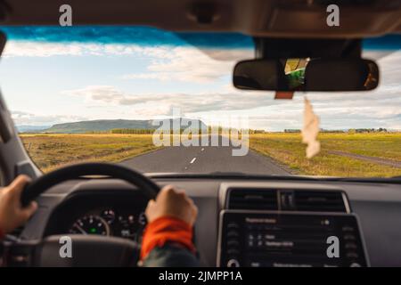 Road trip with man driving a car on highway through the field in the evening at countryside Stock Photo